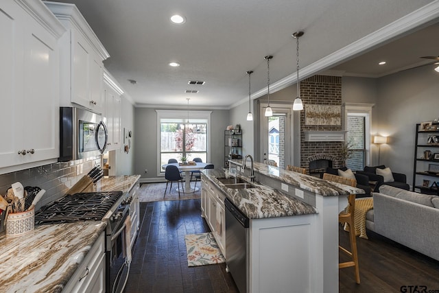 7317 Hearthstone Ln, Tyler, TX 75703 - kitchen with stainless steel appliances, open floor plan, ornamental molding, dark wood-style flooring, and a breakfast bar