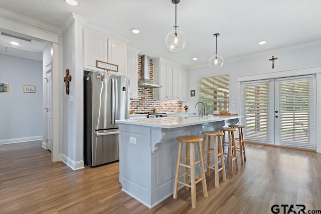 15988 C R 1151, Tyler, TX 75704 - kitchen featuring freestanding refrigerator, wall chimney exhaust hood, wood finished floors, white cabinets, and tasteful backsplash