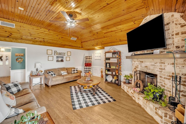 living room with wooden ceiling, ceiling fan, light hardwood / wood-style flooring, a brick fireplace, and vaulted ceiling