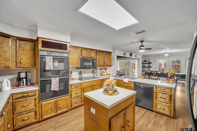 kitchen featuring plenty of natural light, black appliances, light hardwood / wood-style floors, and a kitchen island