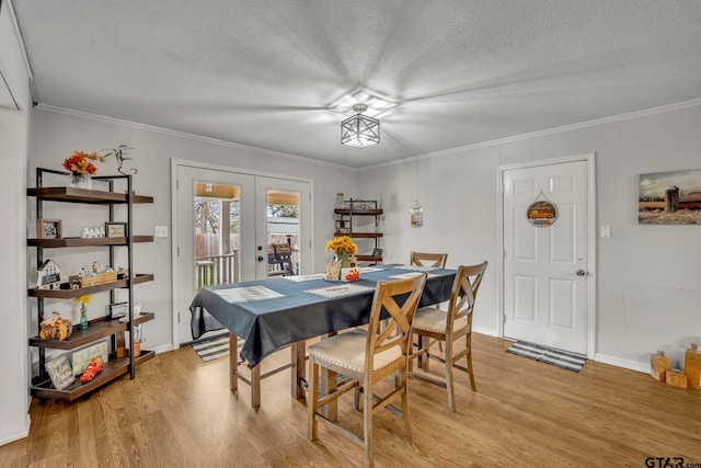 dining room with a textured ceiling, light wood-type flooring, french doors, and ornamental molding