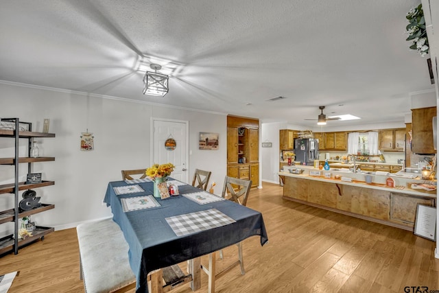 dining area with ornamental molding, light hardwood / wood-style flooring, a textured ceiling, and ceiling fan