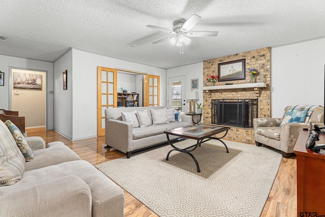 living room featuring ceiling fan, a textured ceiling, and light wood-type flooring