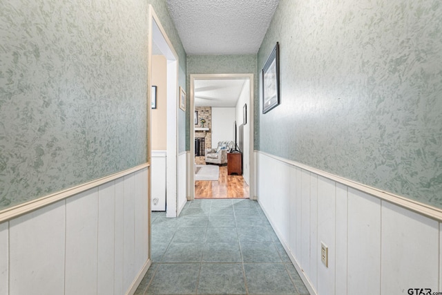 hallway with a textured ceiling and light tile patterned floors