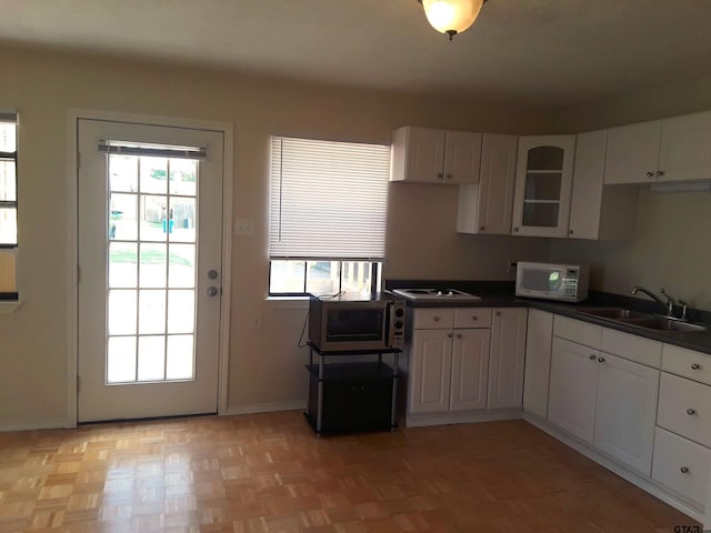 kitchen with white cabinetry, sink, white appliances, and light parquet floors