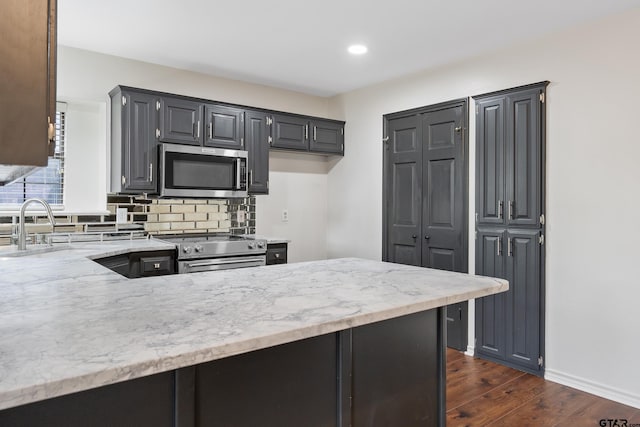 3110 Oleander Dr, Tyler, TX 75707 - kitchen with light stone countertops, stainless steel appliances, backsplash, dark wood-style flooring, and a sink
