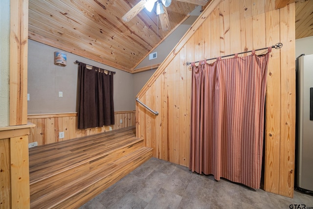 interior space featuring ceiling fan, lofted ceiling, wooden walls, and wooden ceiling