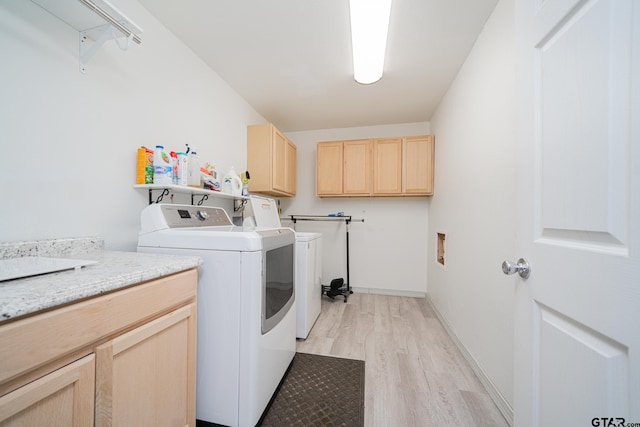 laundry area with separate washer and dryer, light hardwood / wood-style flooring, and cabinets