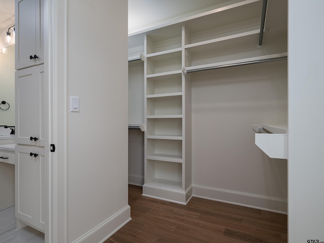 walk in closet with dark wood-type flooring