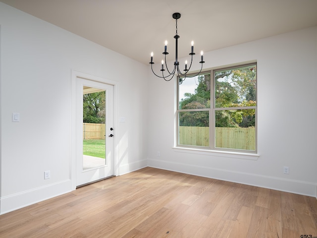 unfurnished dining area featuring light wood-type flooring and a notable chandelier