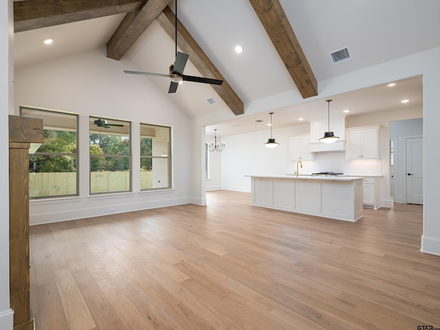 unfurnished living room featuring ceiling fan with notable chandelier, sink, high vaulted ceiling, beam ceiling, and light hardwood / wood-style flooring