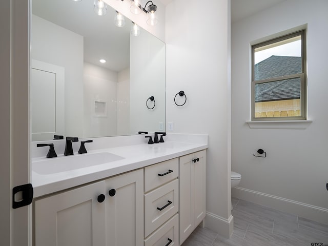 bathroom featuring toilet, vanity, and walk in shower