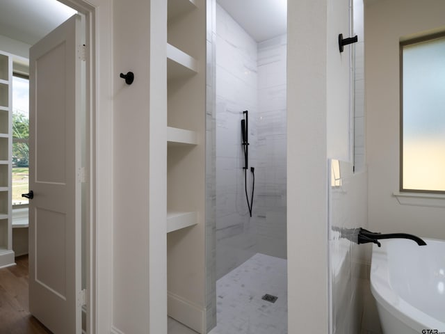 bathroom featuring built in features, shower with separate bathtub, wood-type flooring, and tile walls