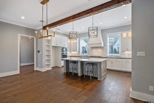 kitchen with white cabinets, dark wood-type flooring, an island with sink, and pendant lighting