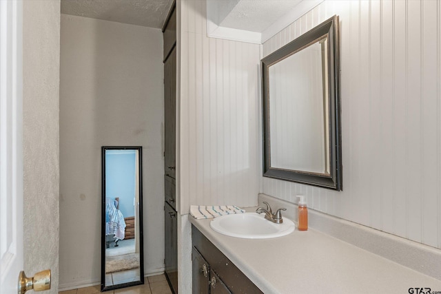 bathroom with tile patterned flooring, vanity, and a textured ceiling