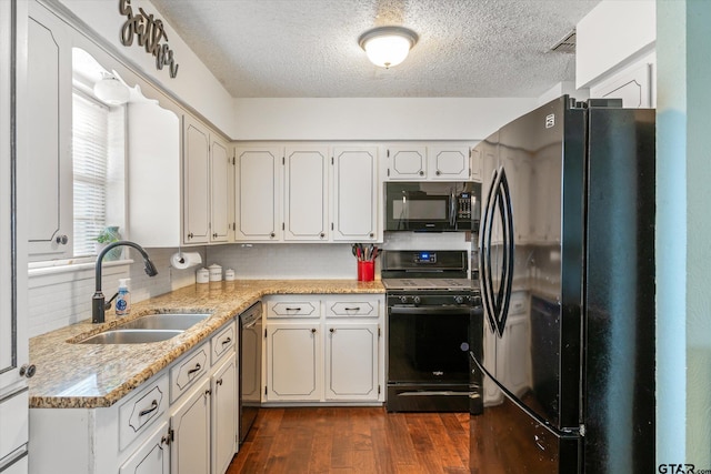 kitchen with tasteful backsplash, sink, white cabinets, black appliances, and dark wood-type flooring