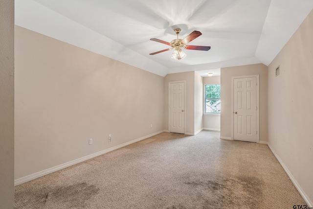 spare room featuring baseboards, a ceiling fan, light carpet, and vaulted ceiling