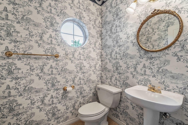 half bathroom with toilet, wallpapered walls, and baseboards