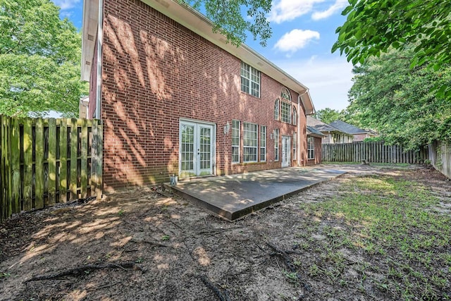 back of property featuring a patio area, french doors, brick siding, and a fenced backyard