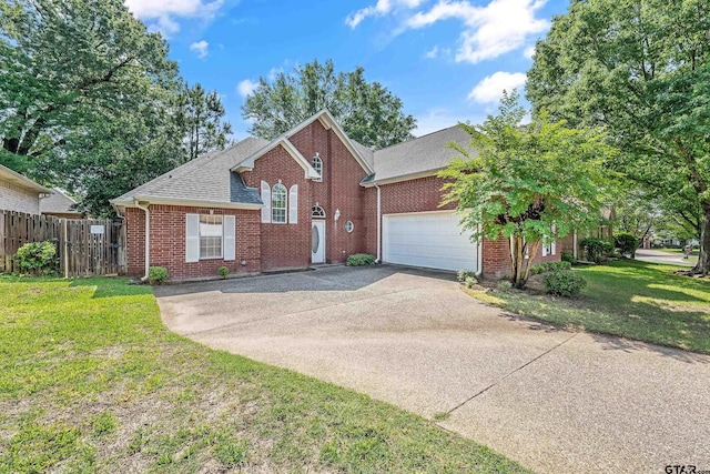 traditional-style home with a front lawn, driveway, brick siding, an attached garage, and fence