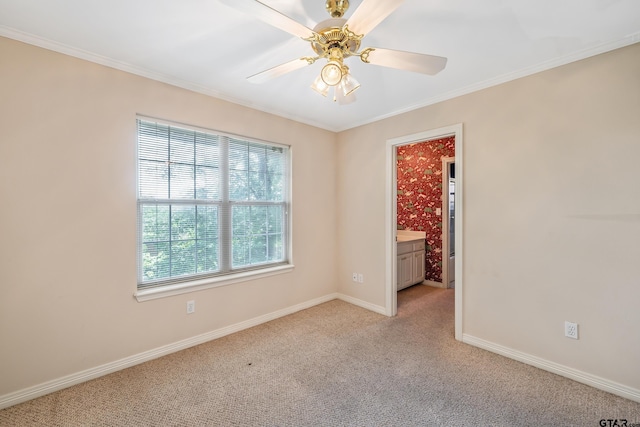 spare room featuring ornamental molding, a ceiling fan, light colored carpet, and baseboards