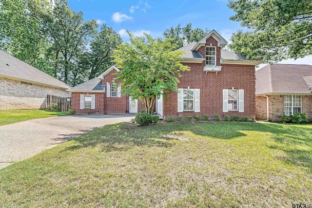 view of front of property with brick siding, fence, a shingled roof, driveway, and a front yard