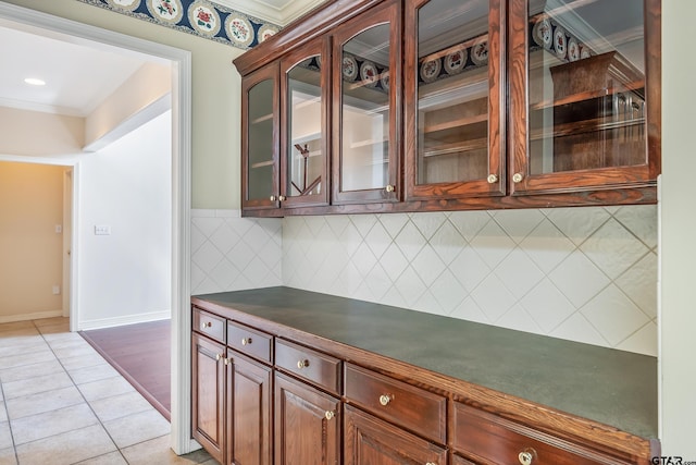 bar with baseboards, light tile patterned floors, ornamental molding, and decorative backsplash