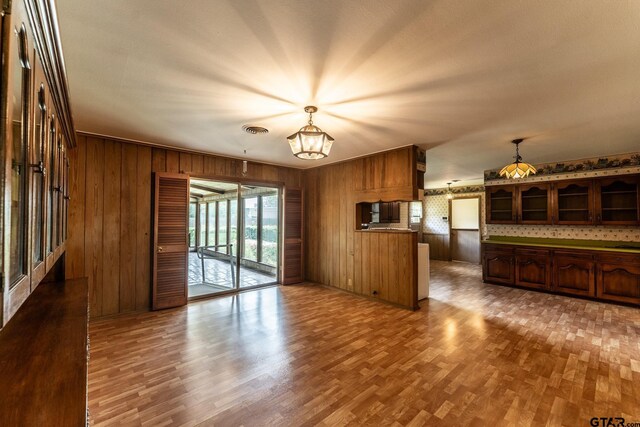 138 Drexel Dr, Sulphur Springs, TX 75482 - unfurnished living room featuring wood walls, a chandelier, healthy amount of natural light, and wood finished floors