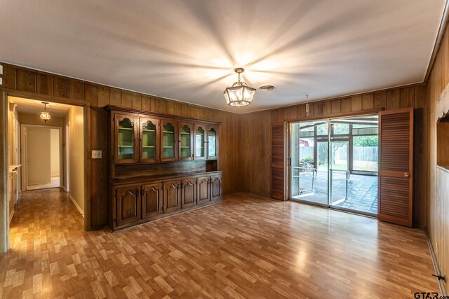 138 Drexel Dr, Sulphur Springs, TX 75482 - unfurnished dining area with wooden walls, light wood finished floors, a chandelier, and baseboards