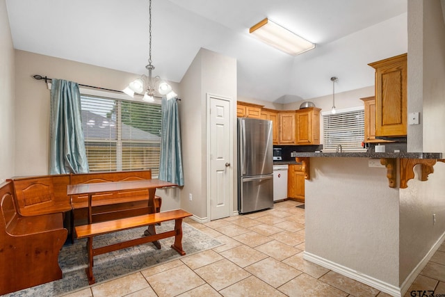 kitchen with lofted ceiling, kitchen peninsula, hanging light fixtures, a breakfast bar, and stainless steel fridge