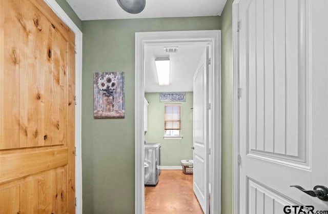 corridor with light wood-type flooring and separate washer and dryer