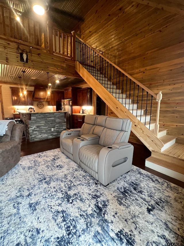 living room with wooden walls, hardwood / wood-style floors, a towering ceiling, and wood ceiling