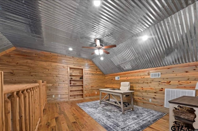 office area featuring wooden walls, ceiling fan, wood-type flooring, and vaulted ceiling