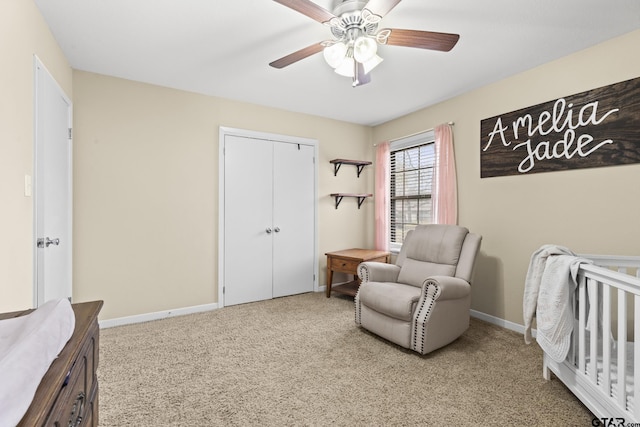 carpeted bedroom with ceiling fan, a closet, and a crib