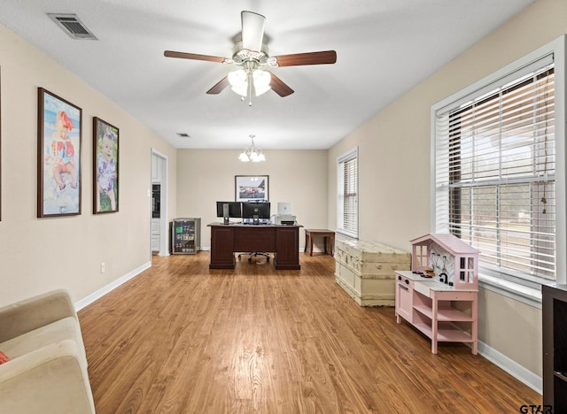 office area with ceiling fan with notable chandelier and light hardwood / wood-style floors