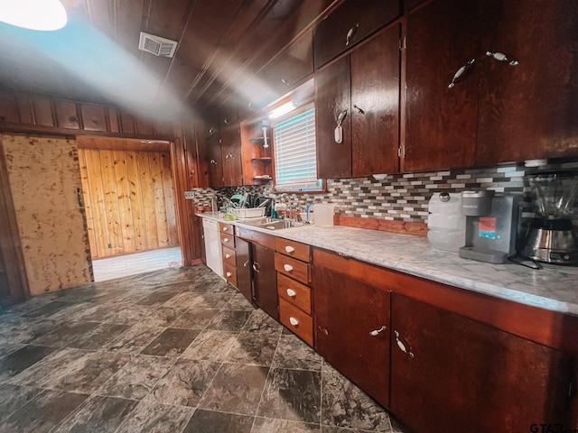 kitchen with wooden walls, sink, lofted ceiling, and decorative backsplash