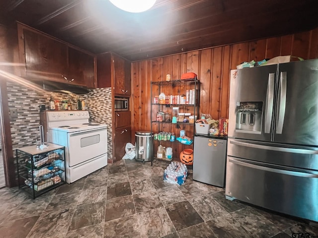 kitchen featuring stainless steel appliances, wooden walls, and backsplash