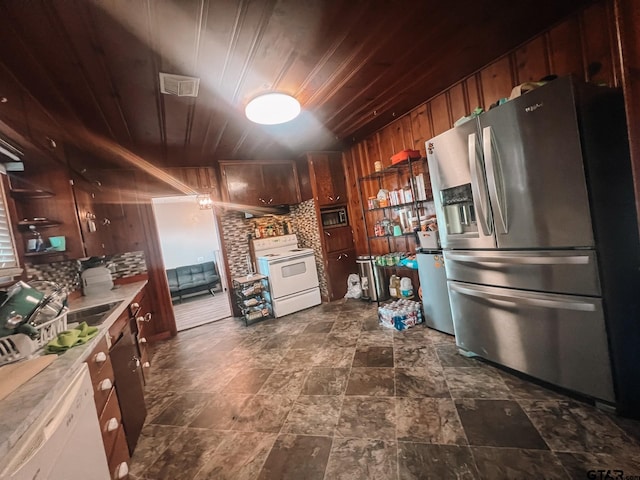 kitchen with white appliances, wood ceiling, wooden walls, and decorative backsplash