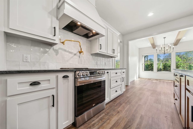 kitchen featuring custom exhaust hood, an inviting chandelier, dark hardwood / wood-style floors, stainless steel electric range oven, and tasteful backsplash