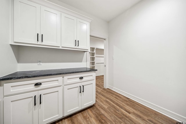 kitchen with dark hardwood / wood-style flooring, white cabinets, and dark stone counters