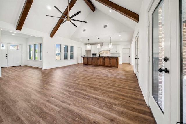 unfurnished living room with beam ceiling, high vaulted ceiling, ceiling fan, and dark wood-type flooring