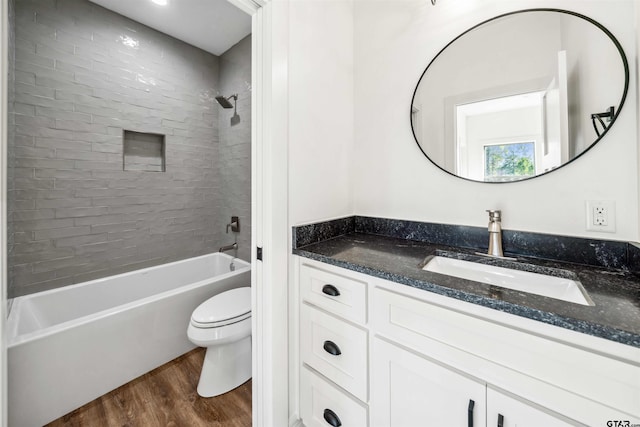 full bathroom featuring hardwood / wood-style floors, tiled shower / bath combo, toilet, and vanity