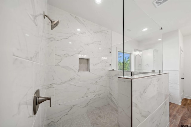 bathroom featuring wood-type flooring and tiled shower