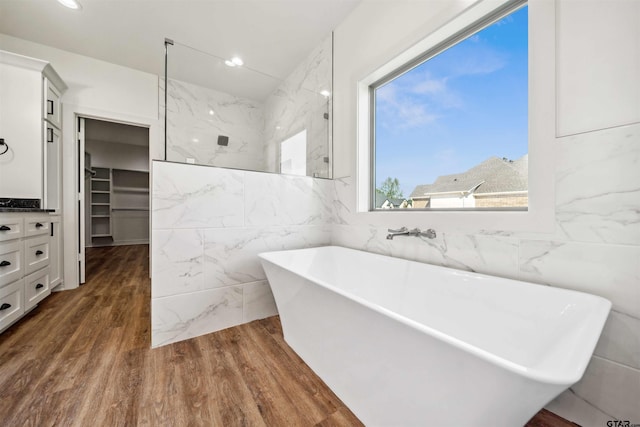 bathroom featuring a bathing tub, tile walls, and a healthy amount of sunlight