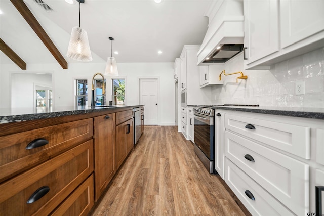 kitchen featuring custom exhaust hood, white cabinets, decorative light fixtures, wood-type flooring, and stainless steel appliances