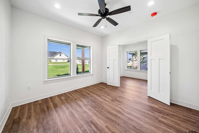 unfurnished room featuring a wealth of natural light, dark hardwood / wood-style flooring, and ceiling fan