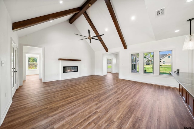 unfurnished living room featuring beamed ceiling, plenty of natural light, dark wood-type flooring, and high vaulted ceiling