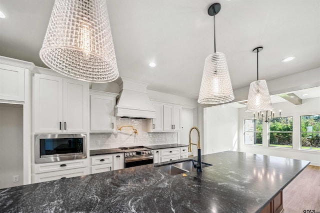 kitchen featuring appliances with stainless steel finishes, sink, pendant lighting, dark hardwood / wood-style floors, and white cabinetry