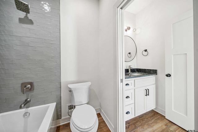 full bathroom with tiled shower / bath, vanity, wood-type flooring, and toilet