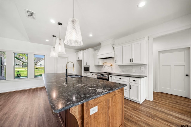 kitchen with white cabinets, custom exhaust hood, sink, and a large island